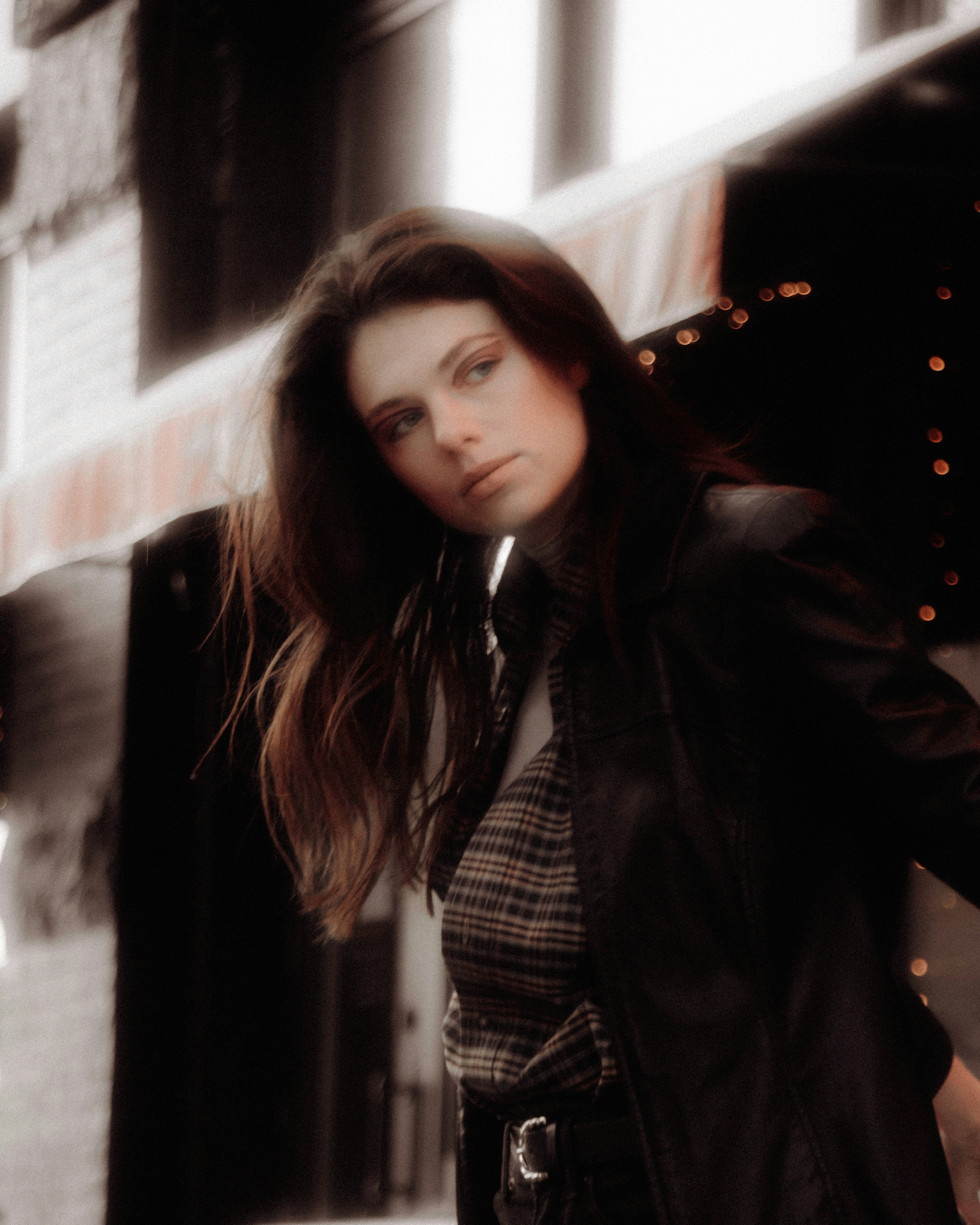 woman in black leather jacket standing near the window